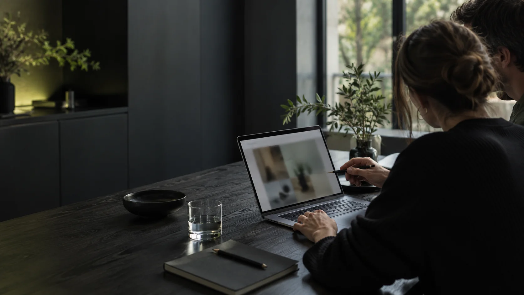 Dwie osoby wspólnie przeglądające laptop i notatki przy stole w pracowni